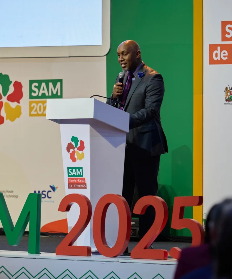 Speaker addressing the SAM 2025 summit from a podium on a branded conference stage